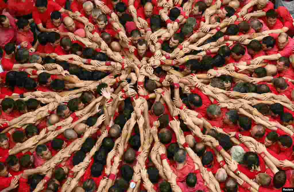 Castellers Colla Joves Xiquets de Valls start to form a human tower called "castells" during the Sant Joan festival at Plaza del Blat square in Valls, south of Barcelona, Spain.