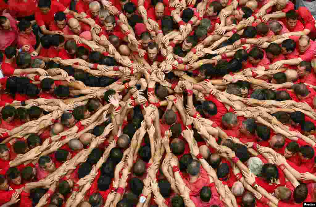 Castellers Colla Joves Xiquets de Valls start to form a human tower called &quot;castells&quot; during the Sant Joan festival at Plaza del Blat square in Valls, south of Barcelona, Spain.