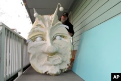 FILE - Thom Karamus shows his papier-mâché head of the hookah-smoking caterpillar from "Alice in Wonderland," Jan. 14, 2021, in New Orleans. All around the city, thousands of houses are being decorated as floats for Mardi Gras.