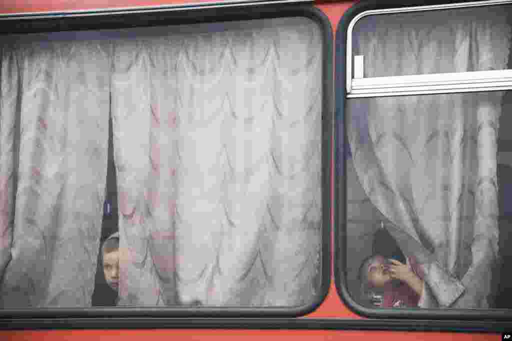 Діти виглядають з вікна автобуса. Біженці з України відправляються з табору поблизу Ростова-на-Дону до міста Іркутськ у Сибіру.