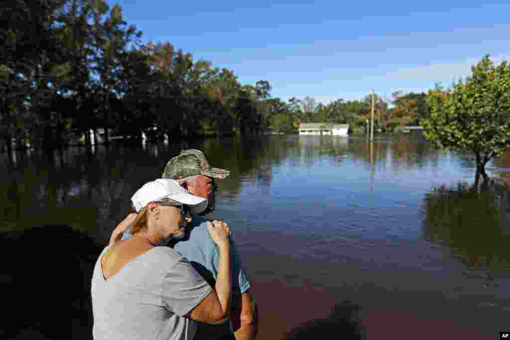 Dianna Wood, embraces her husband Lynn, as they look out over their flooded property as the Little River continues to rise in the aftermath of Hurricane Florence in Linden, North Carolina.