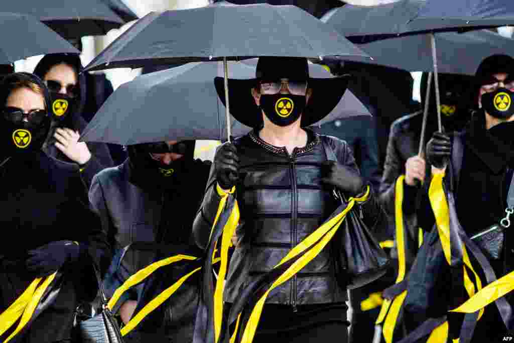 Women wearing black clothing and face masks with radioactivity sign march under umbrellas in Minsk, Belarus, to commemorate the victims of the Chernobyl nuclear disaster on the 35th anniversary of the tragedy.