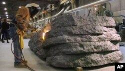 A worker uses a torch to finish a granite monolith at Rock of Ages in Barre, Vt, Jan. 8, 2019. 