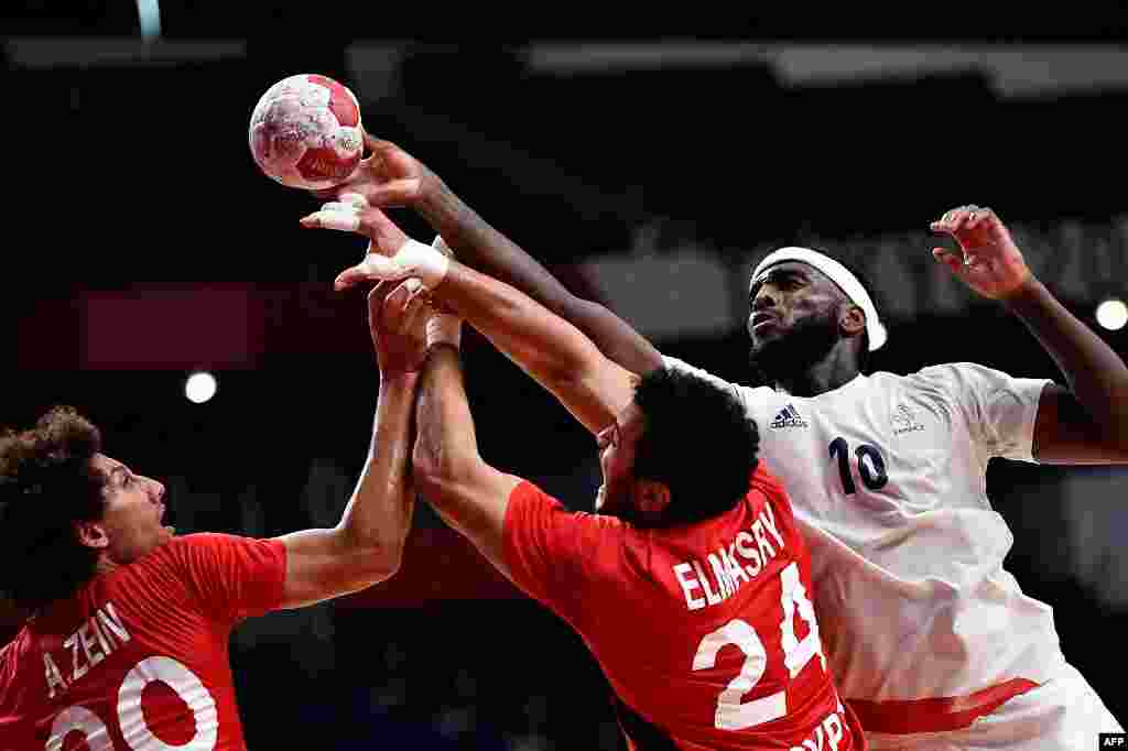 France's right back Dika Mem (R) is challenged by Egypt's left back Ali Mohamed (L) and Egypt's pivot Ibrahim El Masry during the men's semifinal handball match between France and Egypt of the Tokyo 2020 Olympic Games at the Yoyogi National Stadium in Tokyo on August 5, 2021. (Photo by Fabrice COFFRINI / AFP)