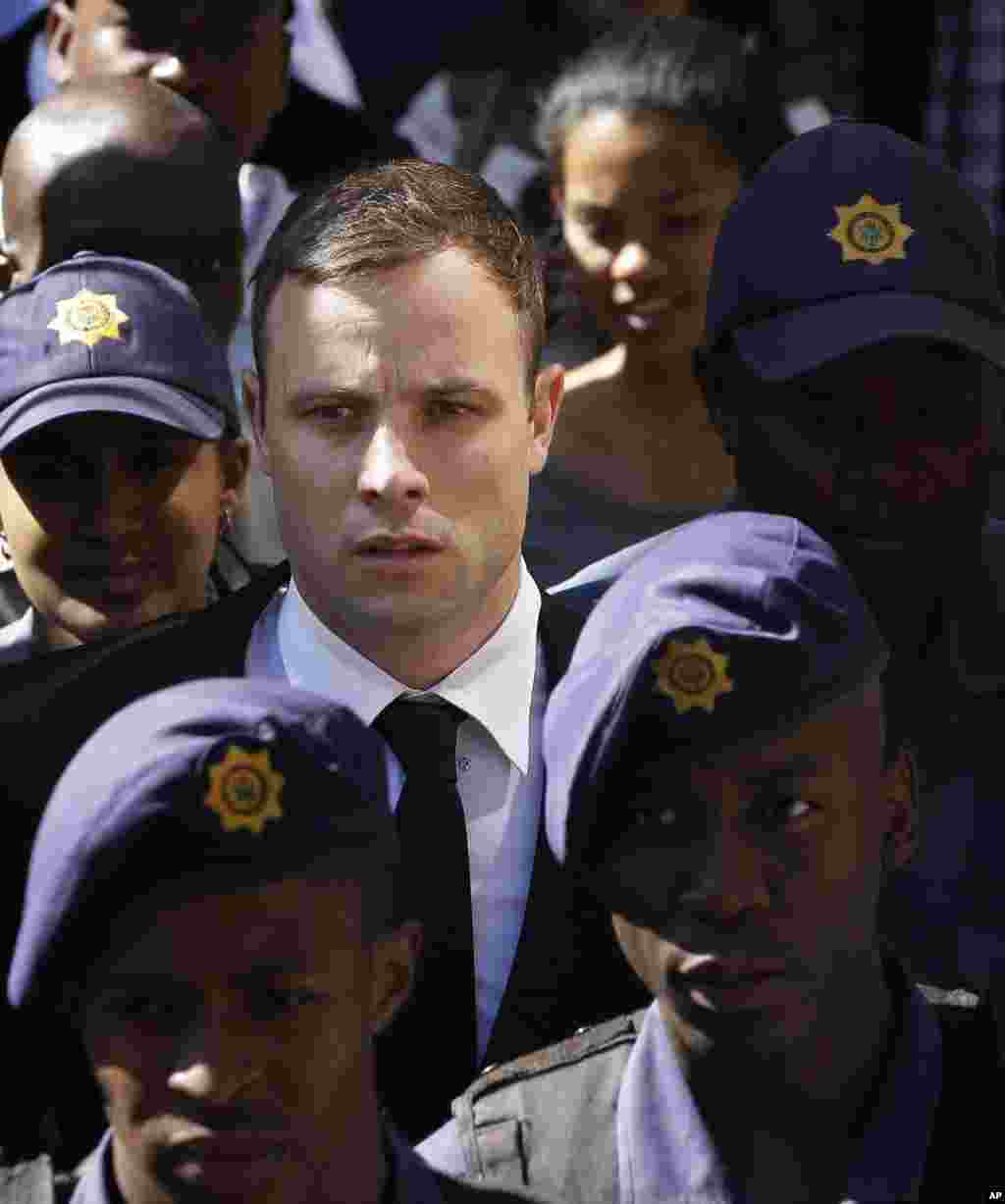 Oscar Pistorius is escorted by police officers as he leaves the high court in Pretoria, South Africa,&nbsp; Oct. 16, 2014. 
