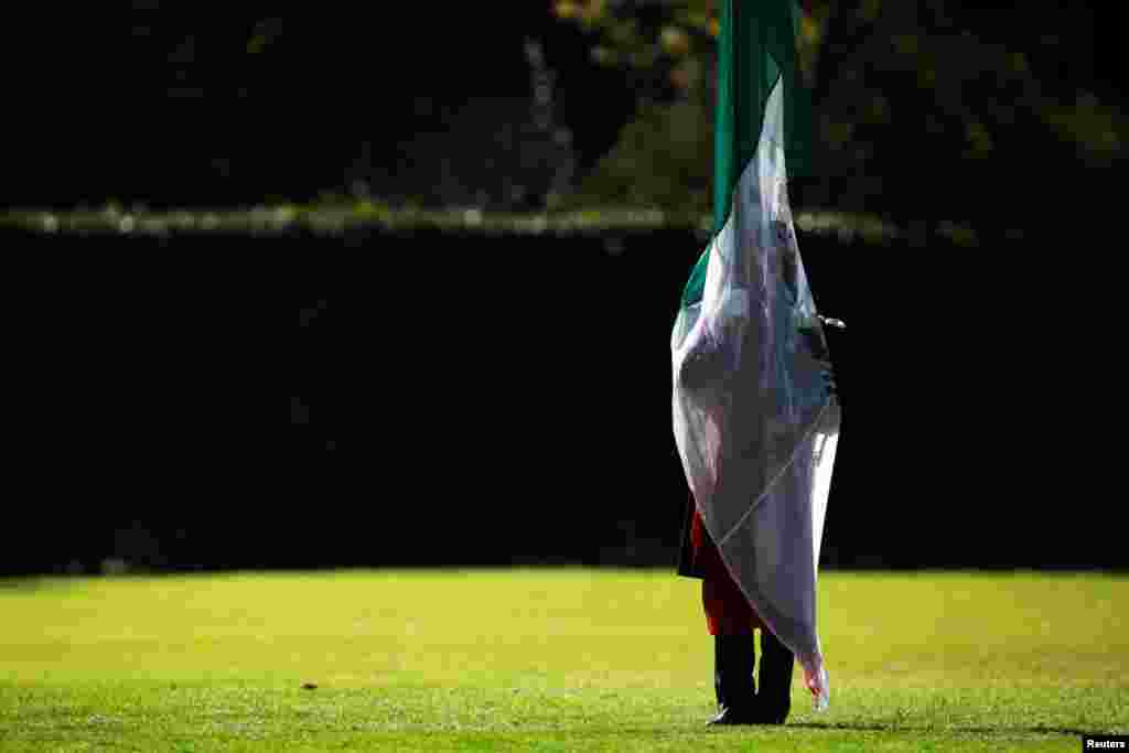 A military cadet is silhouetted while holding a Mexican flag during a troop review by Mexico&#39;s new President Andres Manuel Lopez Obrador at Campo Marte, Mexico City, Dec. 2, 2018.