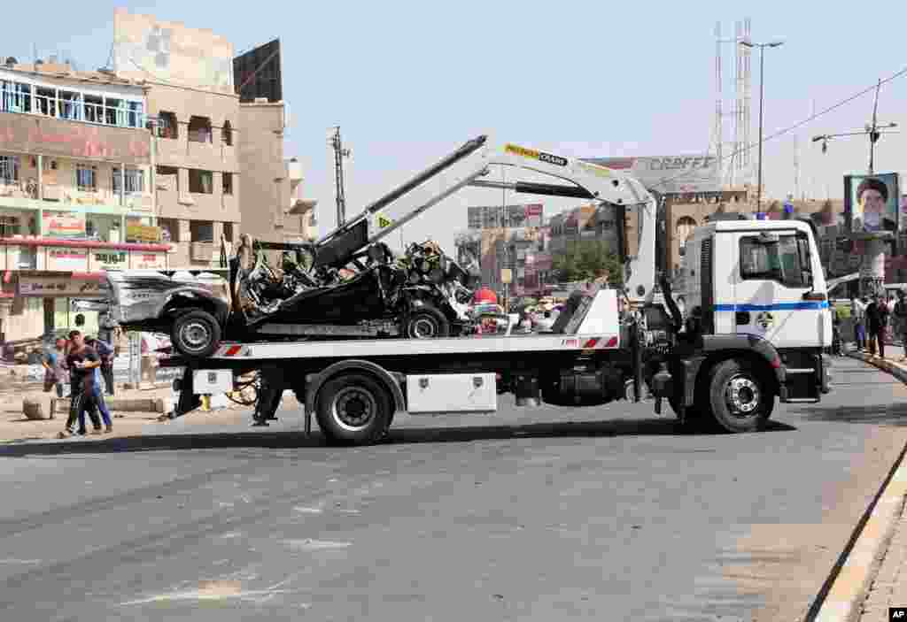Security forces tow away a destroyed car after a car bomb attack in Baghdad, Sept. 30, 2013. 