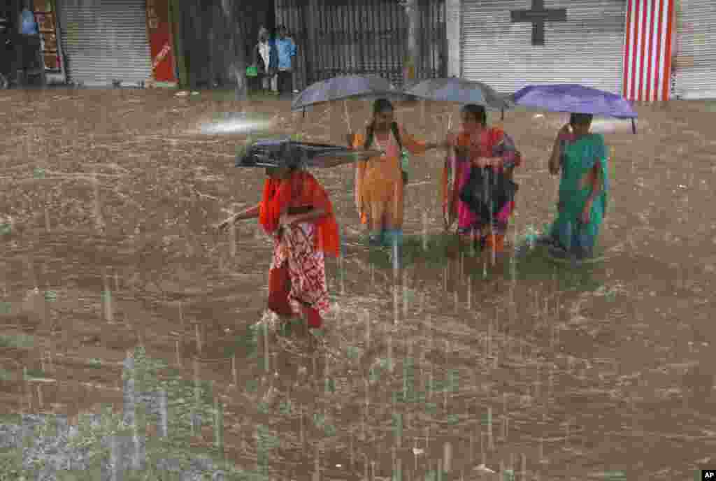 Women hold umbrellas and wade through a waterlogged street in the rain in Hyderabad, India. Monsoon season in India begins in June and ends in October.