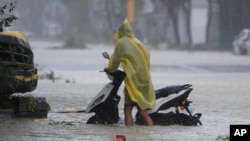 A man pushes a motorbike through a flooded road as Typhoon Krathon makes landfall in Kaohsiung, southern Taiwan, Oct. 3, 2024. 