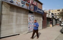 A man walks near empty shops as Syria confirmed its first case of the coronavirus disease (COVID-19), in Damascus, March 23, 2020.