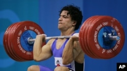FILE - Shahin Nasirinia of Iran lifts in the clean and jerk during the men's 207 lb (94 kg) event at the Nikaia Olympic Weightlifting Hall during the Summer Olympics in Athens, Monday Aug. 23, 2004.