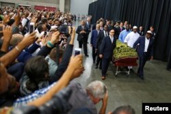 FILE - Worshippers and well-wishers take photographs as the casket with the body of the late-boxing champion Muhammad Ali is brought for his Jenazah, an Islamic funeral prayer, in Louisville, Ky., June 9, 2016.