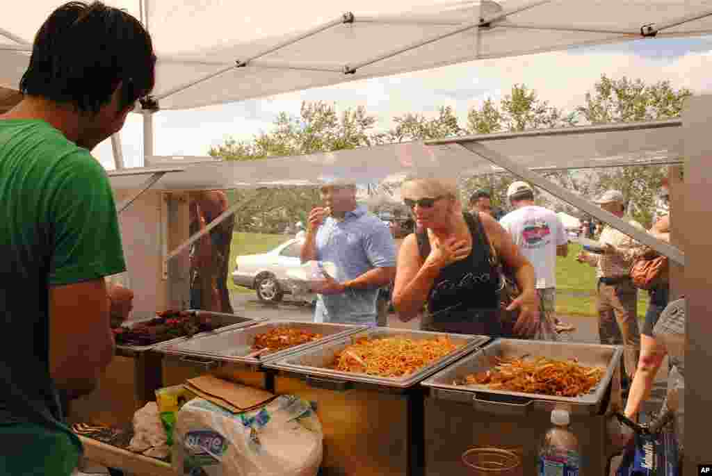 A young Cambodian food vendor looks on as an American visitors is making a choice of food. His food stand is among dozens at the festival that both caters to visitors and help keep the festival going annually.