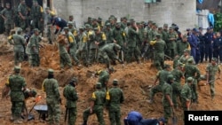 Binh sĩ tìm kiếm người sống sót sau khi một chiếc xe buýt và hai ngôi nhà bị chôn vùi bởi một vụ đất chuồi ở Altotonga trong bang Veracruz, dọc bờ biển Vịnh Mexico, ngày 16/9/2013.