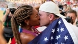 Tara Davis-Woodhall and husband Hunter Woodhall kiss after she won the silver medal for the U.S. in the women's long jump final at the World Athletics Championships in Hungary, Aug. 20, 2023. They have been called track and field's power couple. (AP Photo/Matthias Schrader, File)