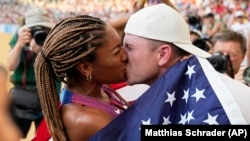 Tara Davis-Woodhall and husband Hunter Woodhall kiss after she won the silver medal for the U.S. in the women's long jump final at the World Athletics Championships in Hungary, Aug. 20, 2023. They have been called track and field's power couple. (AP Photo/Matthias Schrader, File)