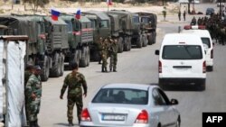 Des soldats syriens et russes attendent à l'entrée du camp de Wafideen, dans la Ghouta orientale, le 12 avril 2018.