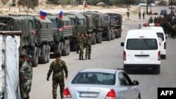 Des soldats syriens et russes attendent à l'entrée du camp de Wafideen, dans la Ghouta orientale, le 12 avril 2018.