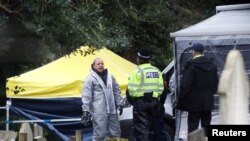 Anggota dinas darurat (mengenakan pakaian pelindung) di lokasi makam Liudmila Skripal, istri mantan perwira intelijen Rusia Sergei Skripal, di London Road Cemetery, di Salisbury, Inggris, 10 Maret 2018.