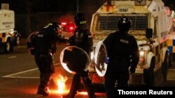 Policías irlandeses se protegen de una bomba de gasolina arrojada por jóvenes manifestantes molestos por las repercusiones del Brexit, entre otros temas.