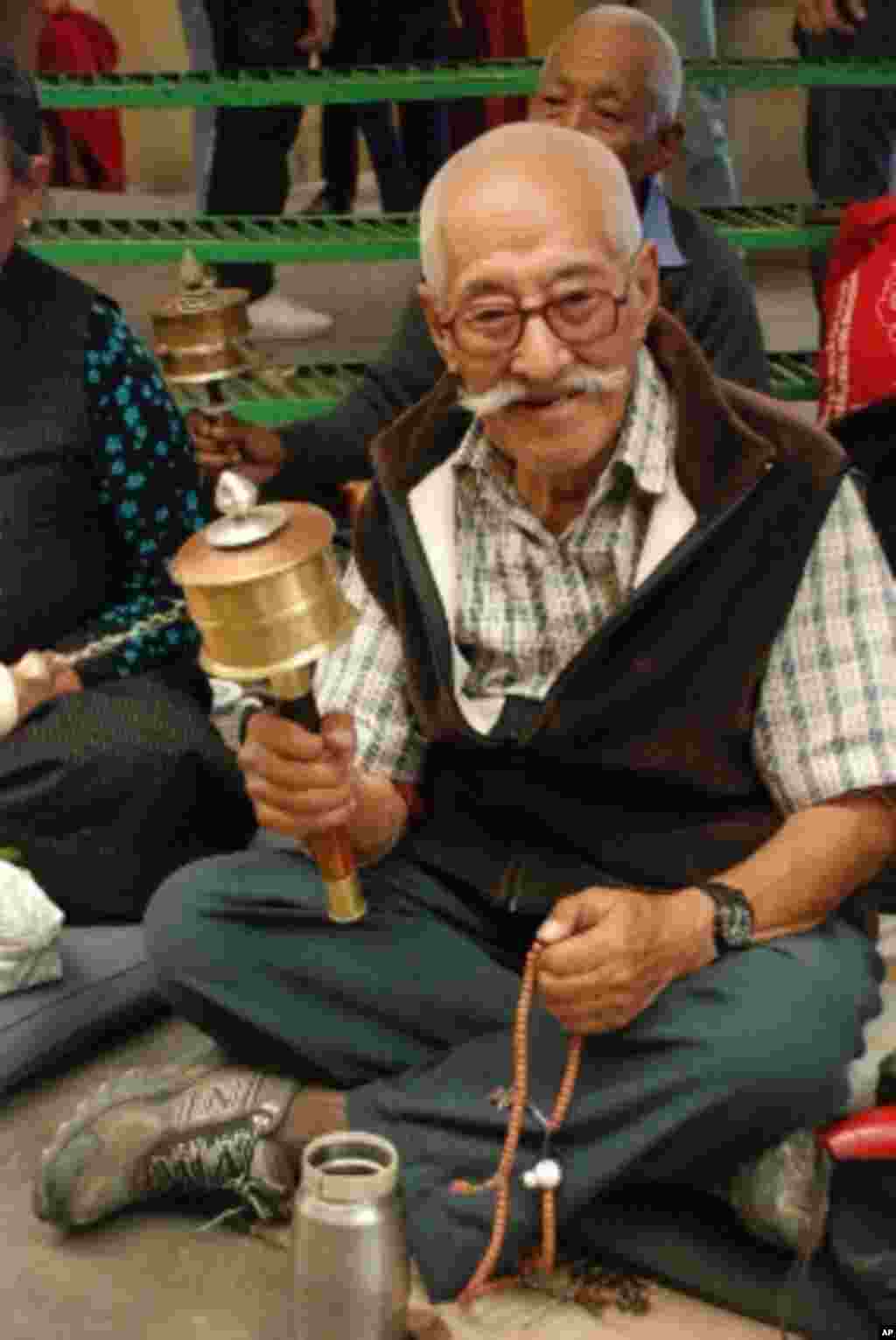 手持轉經筒在祈禱的藏傳佛教信徒