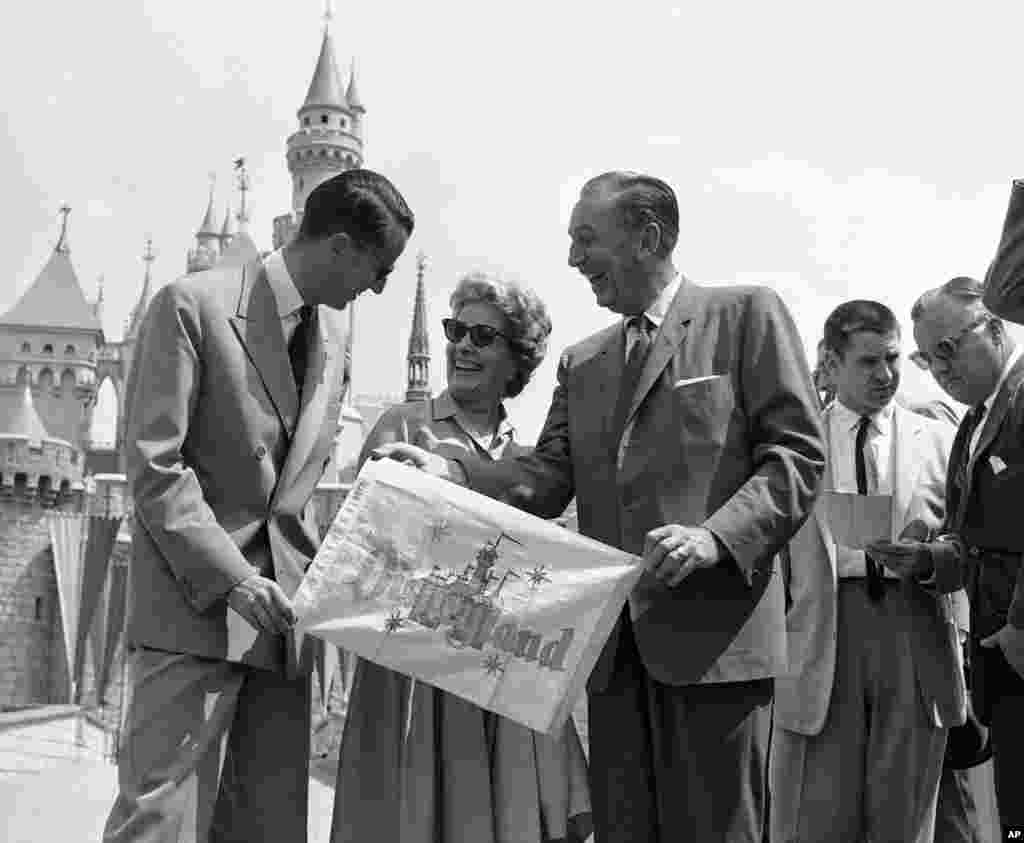 Walt Disney and his wife present King Baudouin of Belgium with a memento of his visit as they welcome him to Disneyland in Anaheim, May 20, 1959. Disney gave the visiting monarch a personally-conducted tour through the amusement park and took him on some 