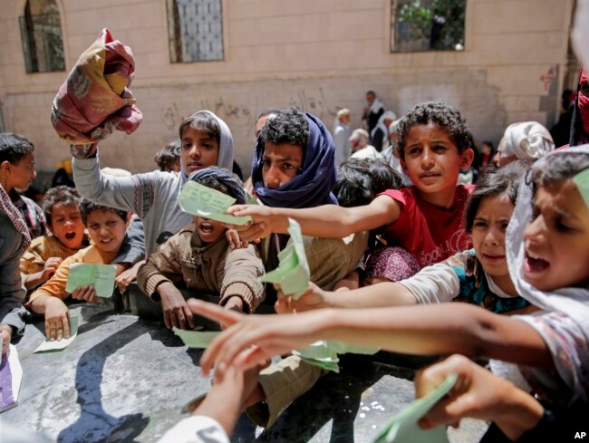 Yemenis present documents in order to receive food rations provided by a local charity, in Sanaa, Yemen.
