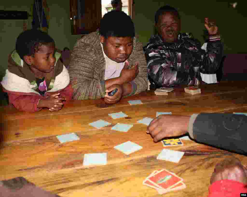  Sihle plays a card game with other residents and as usual, he’s full of jokes (VOA/ D. Taylor)