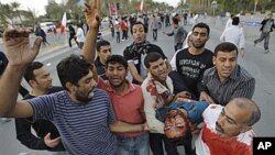 An unidentified Bahraini anti-government protestor is carried to a vehicle to be taken to a hospital after being wounded during a demonstration in Manama, Bahrain, February 18, 2011