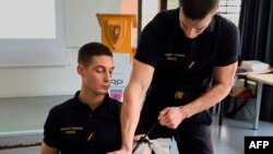 FILE - Firefighters show visitors how to place a tourniquet as part of a training in first aid in case of terrorist attacks, Jan.16, 2016 in Paris. Americans are gleaning those tips and others as they pack classes on how to react to and survive a shooting.