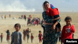 Displaced people from the minority Yazidi sect, fleeing violence from forces loyal to the Islamic State in Sinjar town, walk towards the Syrian border.