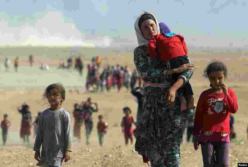 Displaced people from the minority Yazidi sect, fleeing violence from forces loyal to the Islamic State in Sinjar town, walk towards the Syrian border, on the outskirts of Sinjar mountain, near the Syrian border town of Elierbeh of Al-Hasakah Governorate 