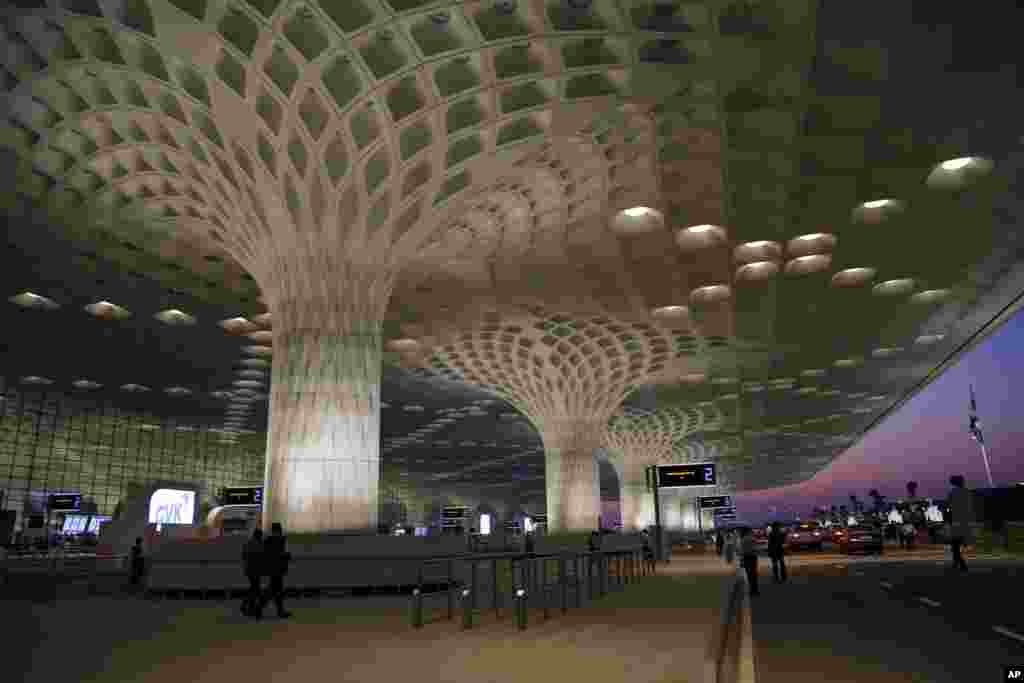 Orang-orang berlalu-lalang di luar T2, terminal baru terpadu Bandara Chhatrapati Shivaji, saat pembukaan terminal itu di Mumbai. Ibukota India yang padat itu membuka terminal bandara yang telah ditunggu-tunggu dan bernilai $ 2 milyar itu pada hari Jumat. 