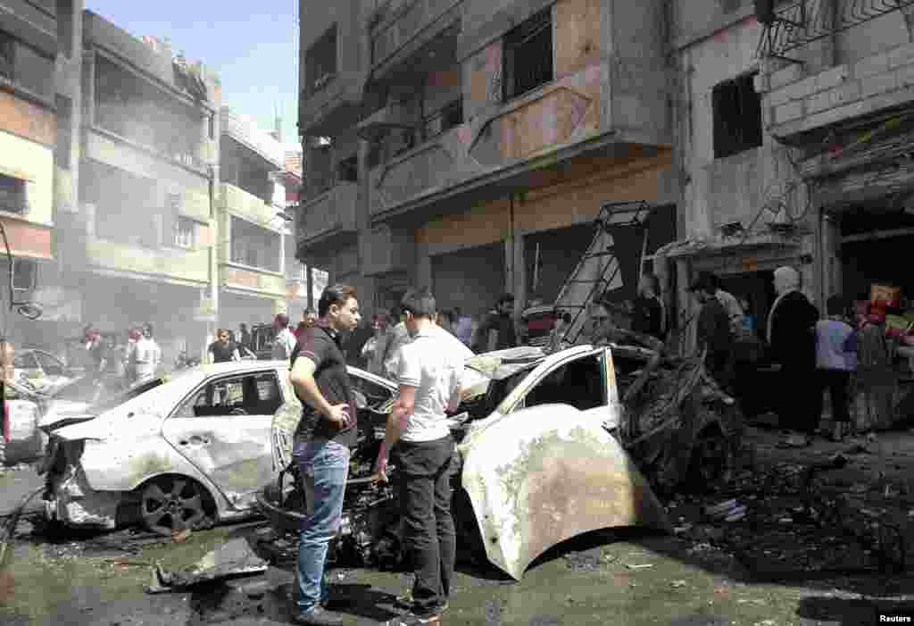 People gather at the site of two car bomb attacks at al-Abassia roundabout in Homs, April 29, 2014. (SANA)