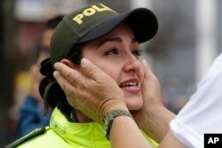 Un hombre que asiste a una marcha para repudiar el terrorismo abraza a una policía que llora mientras realiza una patrulla de seguridad para la marcha, en Bogotá, Colombia, el domingo 20 de enero de 2019.