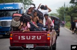 Honduran migrants who are traveling to the U.S. as a group get a free ride in the back of a truck as they make their way through Zacapa, Guatemala, Oct. 17, 2018.