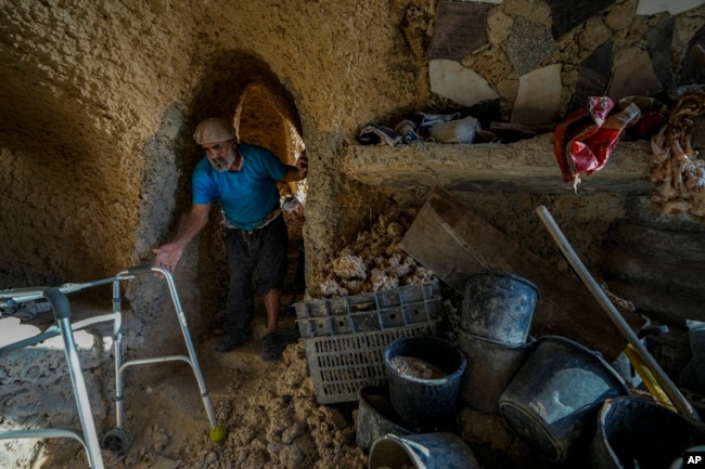 Nissim Kahlon reaches to his walking device in his home chiseled out of the sandstone cliffs overlooking the Mediterranean sea in Herzliya, Israel, Wednesday, June 28, 2023. (AP Photo/Ariel Schalit)