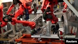 FILE - Robots work on the cab of a 2019 Ram pickup at the Fiat Chrysler Automobiles Sterling Heights Assembly Plant in Sterling Heights, Mich., Oct. 22, 2018.