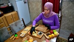 File - Fatima Ali prepares cheese-plate takeaway at her home kitchen in Baghdad, Iraq, Nov. 28, 2020. She is among a growing numbers of Iraqi women who are finding some good under the movement restrictions imposed because of the coronavirus pandemic.
