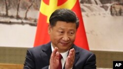 Chinese President Xi Jinping claps while addressing the media as he introduces new members of the Politburo Standing Committee at Beijing's Great Hall of the People Wednesday, Oct. 25, 2017.