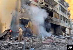 Firefighters try to extinguish a fire as smoke rises from a destroyed building that was hit in an Israeli airstrike in Dahiyeh, in the southern suburb of Beirut, Lebanon, Nov. 14, 2024.