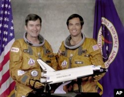 In this undated photo made available by NASA, STS-1 crew John Young, left, and Robert Crippen, hold a model of the space shuttle. NASA says Young, who walked on the moon and later commanded the first space shuttle flight, died Jan. 5, 2018. He was 87.