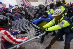 FILE - In this Jan. 6, 2021, file photo, violent insurrectionists loyal to President Donald Trump hold on to a police barrier at the Capitol in Washington.
