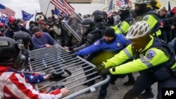 ARCHIVO - En esta fotografía del 6 de enero de 2021, insurrectos violentos leales al presidente Donald Trump se aferran a una barrera policial en el Capitolio en Washington.