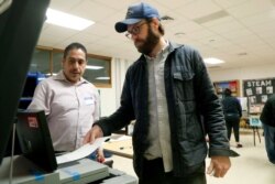 Dallas County election worker Maxx Nuñez helps Democrat Jamie Wilson cast his ballot in the Super Tuesday primary at John H. Reagan Elementary School in the Oak Cliff section of Dallas, March 3, 2020.