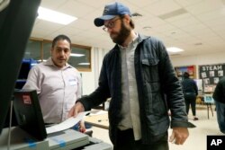 Dallas County election worker Maxx Nuñez helps Democrat Jamie Wilson cast his ballot in the Super Tuesday primary at John H. Reagan Elementary School in the Oak Cliff section of Dallas, March 3, 2020.