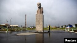 FILE - A woman walks past a statue of Soviet state founder Vladimir Lenin in Yuzhno-Kurilsk, the main settlement on the Southern Kuril island of Kunashir, Sept. 17, 2015. 