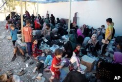 FILE - Displaced women and children sit on the ground at a collection point for internal refugees west of Mosul, Iraq, Aug. 12, 2017.
