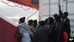 FILE - Men wait to disembark from the Ocean Viking ship as it reaches the port of Messina, Italy, Sept. 24, 2019.