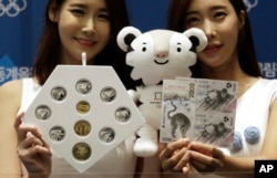 Models pose with the commemorative coins and bank notes for the 2018 Winter Olympic Games during the launching ceremony in Seoul, South Korea, Sept. 1, 2017.